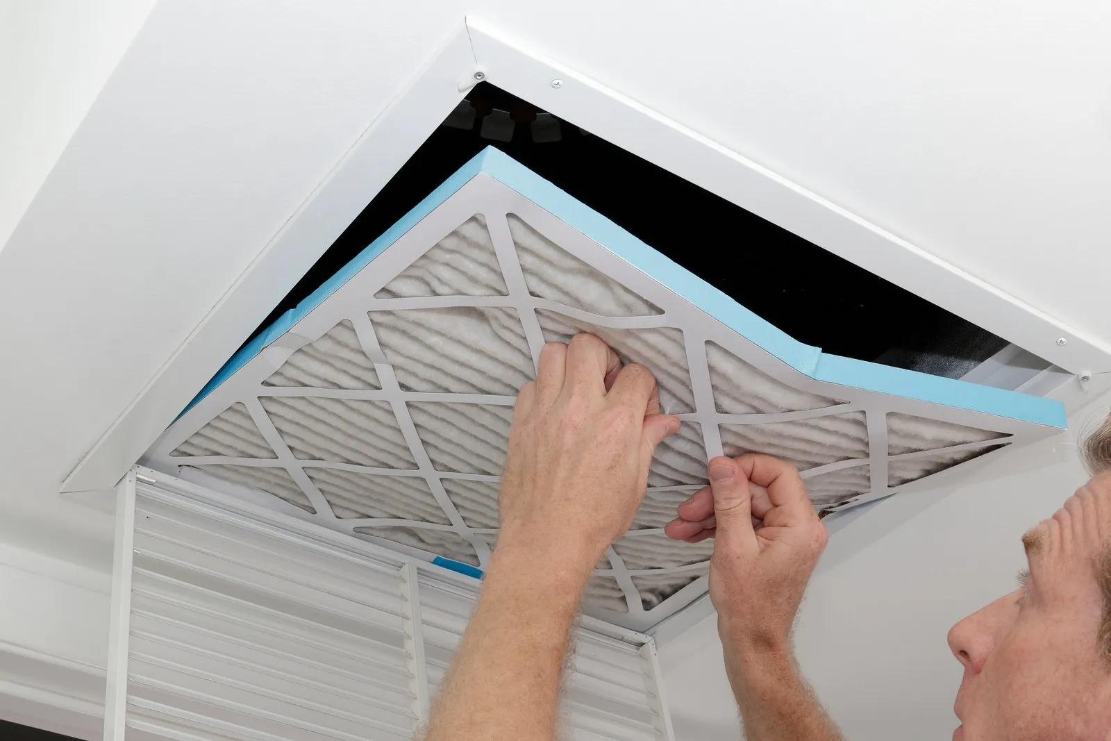 Technician cleaning an air duct vent in a Littleton home